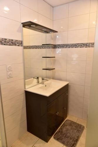 une salle de bain avec un lavabo et un miroir dans l'établissement Appartement avec pergola, à Jû-Belloc