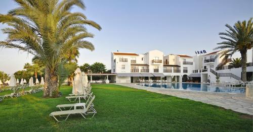 a resort with lawn chairs and a swimming pool at Akti Beach Hotel & Village Resort in Paphos City