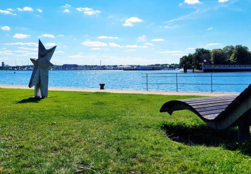 a bench in a park next to a body of water at Hafenromantik pur - Exklusive Ferienwohnung mit erstklassigem Blick von "Momentic" in Neustadt in Holstein