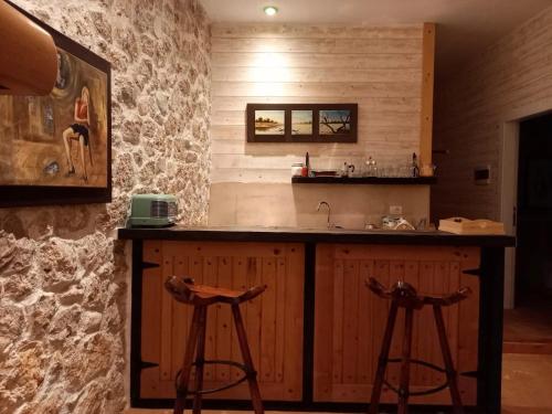 a kitchen with two bar stools and a sink at Rahoni Park & Suites in Dhërmi