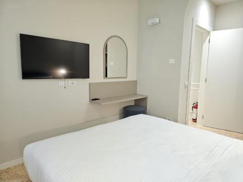 a bedroom with a white bed and a flat screen tv at Andreola Central Hotel in Milan