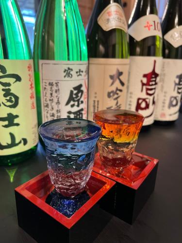 two glass vases sitting on a red tray with bottles of wine at すいこうえんさくら in Fujinomiya