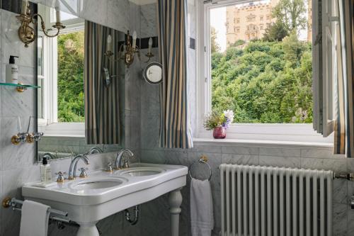 a bathroom with a sink and a window at AMERON Neuschwanstein Alpsee Resort & Spa in Schwangau