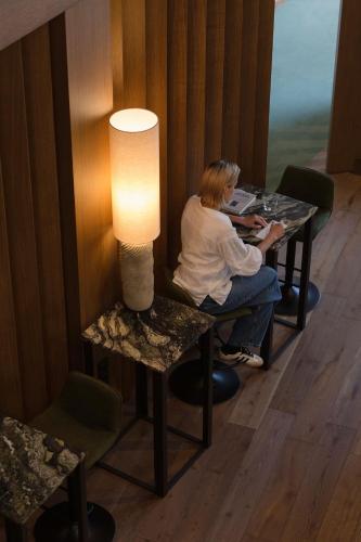 a woman sitting at a table with a lamp at Monist Palanga boutique by SPA VILNIUS in Palanga