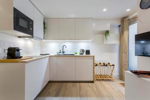 une cuisine avec des armoires blanches et un évier dans l'établissement Cozy Studio - Heart of the Traboule, à Lyon