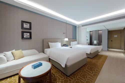 una camera d'albergo con due letti e un divano di Wyndham Grand Plaza Royale Hot Springs Fenghuang a Fenghuang