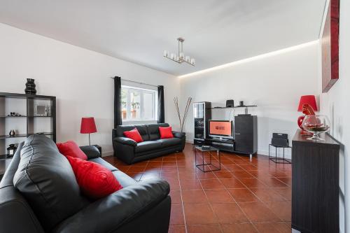 a living room with a black leather couch and red pillows at GuestReady - Esposende Dreamy Retreat in Esposende