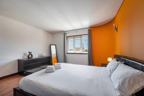a bedroom with a large white bed with an orange wall at GuestReady - Esposende Dreamy Retreat in Esposende