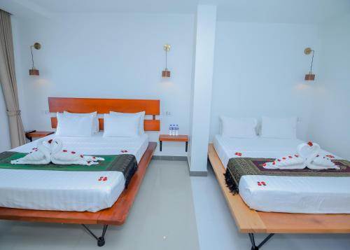 two beds in a room with white walls at Bliss & Beats Hostel in Phnom Penh