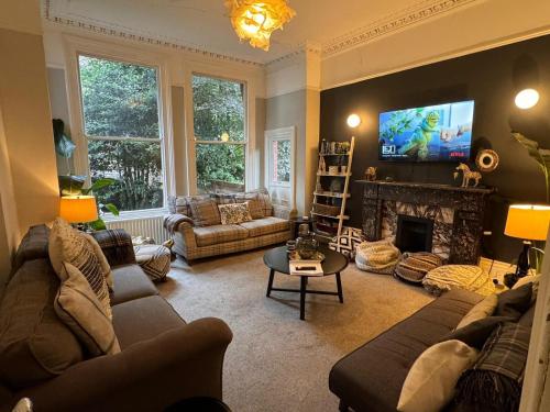 a living room with couches and a fireplace with a tv at Deluxe Huge Detached House with Parking, sleeps up to 30 people, 2m from Liverpool City Centre in Liverpool