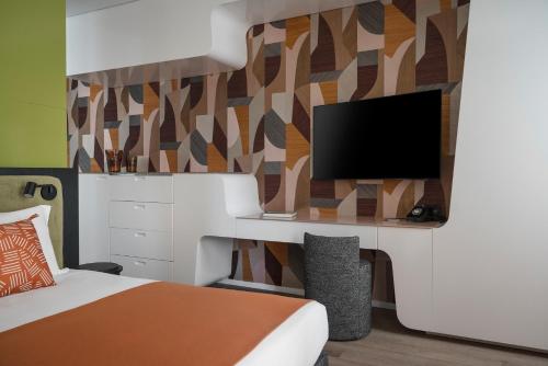 a bedroom with a bed and a flat screen tv at DuoMo Hotel in Rimini