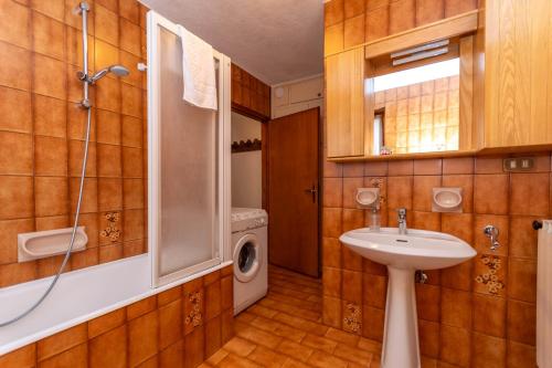 a bathroom with a sink and a washing machine at Lodge Auta in Falcade
