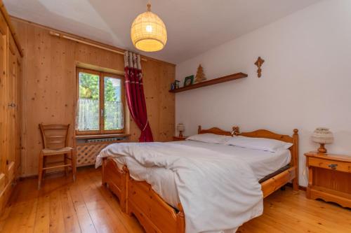 a bedroom with a large bed and a chair at Lodge Auta in Falcade