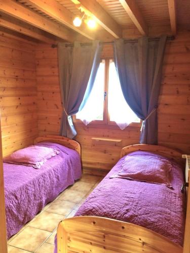 two beds in a log cabin with a window at Le gite du gabelou in Hargnies