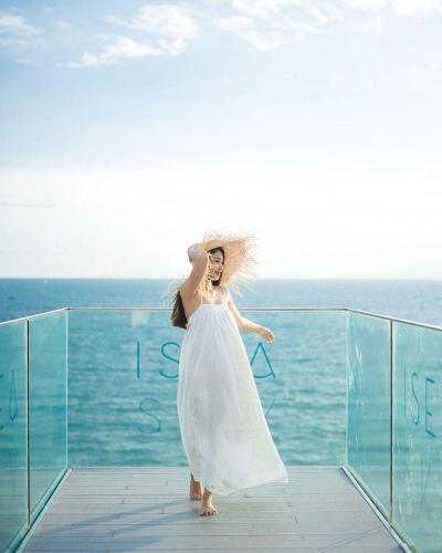 a woman in a white dress standing on a balcony with the ocean at Veranda Pattaya Sea View Jomtien Beach Front วิวทะเล พัทยา จอมเทียน in Na Jomtien