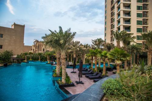 una piscina con palmeras y un edificio en Lagoona Beach Luxury Resort and Spa, en Manama