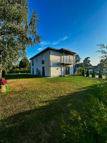 a house on a grassy field with a tree at Apartamenti Zaķi in Saulkrasti