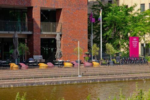 a building with tables and chairs next to a river at Crowne Plaza Amsterdam - South by IHG in Amsterdam