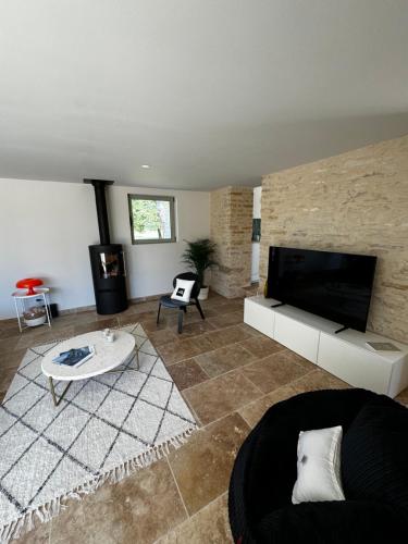 un salon avec une télévision et un canapé dans l'établissement La Grange d Ulysse, à Crayssac