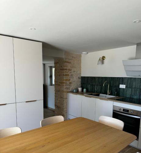 une cuisine avec des armoires blanches et une table en bois dans l'établissement La Grange d Ulysse, à Crayssac