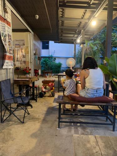 a woman and a child sitting on a bench at บ้านใจแปงโฮมสเตย์ Ban Jaipang Homestay in Pai