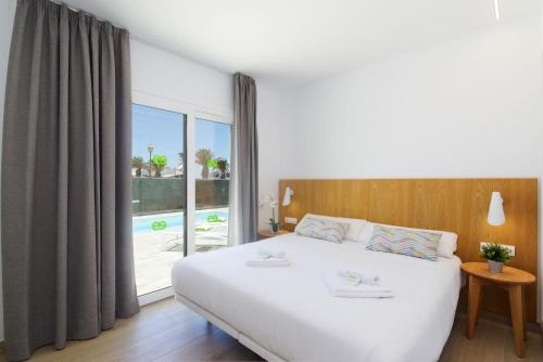 Un dormitorio con una cama blanca y una ventana grande. en Ereza Villas Artenara, en Playa Blanca