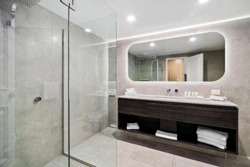 a bathroom with a shower and a sink and a mirror at Quality Hotel Parklake Shepparton in Shepparton
