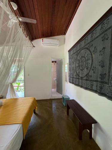 a bedroom with a bed and a bench on a wall at Pousada Horizonte Azul in Ilha de Boipeba