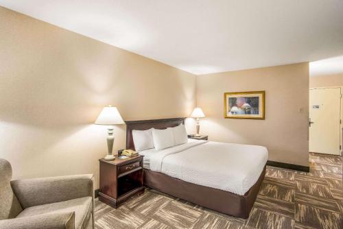 a hotel room with a bed and a chair at Clarion Inn Grand Junction Airport in Grand Junction