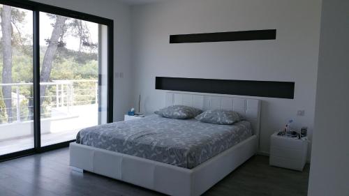 une chambre blanche avec un lit et une grande fenêtre dans l'établissement Villa des Anges, à Draguignan