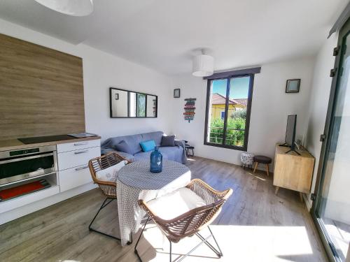 un soggiorno con un divano e un tavolo di La Fossette - T2 avec terrasse, parking et wifi a Le Lavandou