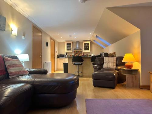 a living room with leather furniture and a kitchen at The Steadings in Kinlochleven