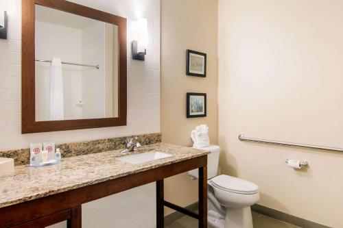 a bathroom with a toilet and a sink and a mirror at Comfort Inn & Suites - Independence in Independence
