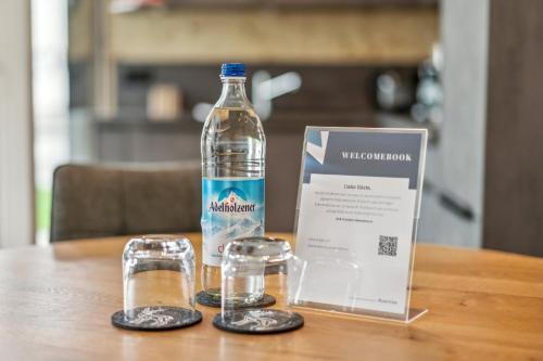 a bottle of water and two glasses on a table at Chalet LebensTraum im Zentrum in Oberstaufen