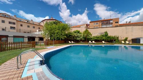 a large swimming pool with chairs and a building at AZZ Peñafiel Las Claras Hotel & Spa in Peñafiel