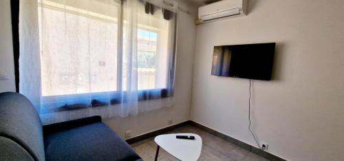 un salon avec un canapé, une télévision et une fenêtre dans l'établissement 3 Le Saint Joseph studio in city center of Antibes with AC, à Antibes
