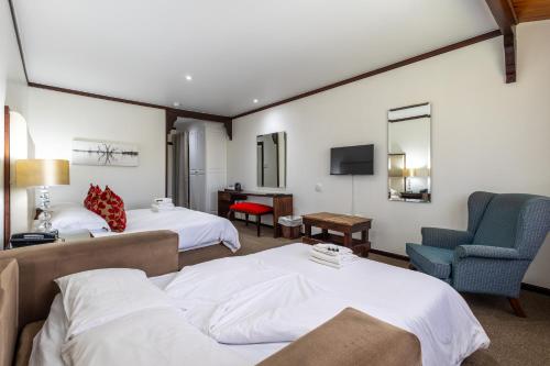 a hotel room with two beds and a chair at Knysna Log-Inn Hotel in Knysna