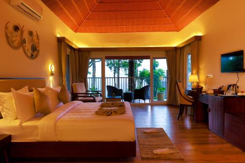 a bedroom with a bed and a living room at Silent Brook Resort - Coorg in Madikeri