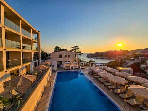 a view of a hotel with a swimming pool and the sunset at The New Hotel Mediteran - VILLA Edition in Ulcinj