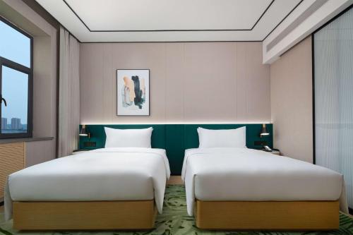 two beds in a hotel room with two beds sidx sidx sidx at Hilton Garden Inn Hulunbuir Hailar in Hulunbuir
