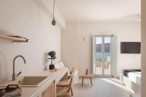 a white kitchen with a sink and a table at Yerma Suites Limeni in Limeni