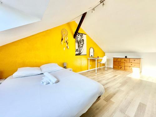 une chambre avec un lit blanc et un mur jaune dans l'établissement L'Urban Spot, calme et lumineux, à Limoges
