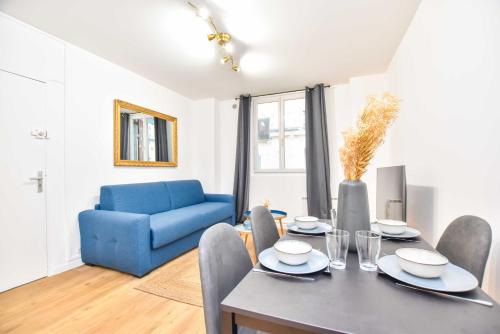 une salle à manger avec une table et un canapé bleu dans l'établissement Cosy studio - 2P - Voltaire, à Paris