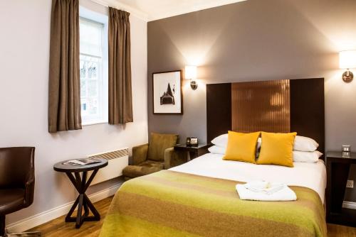 a hotel room with a bed and a chair at De Vere Horsley Estate in Leatherhead