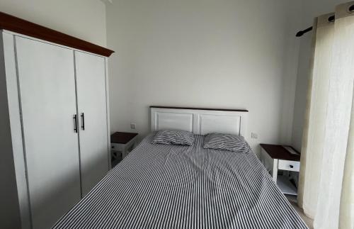 a bed in a white room with a striped mattress at Canterbury Golf Resort Apartments in Kahatuduwa