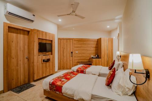 a bedroom with two beds and a flat screen tv at Hotel Amantran Inn - City Centre in Udaipur