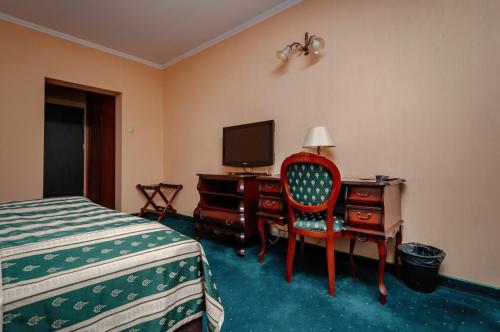 a bedroom with a bed and a desk and a television at Hotel Chopin Business&SPA in Sochaczew