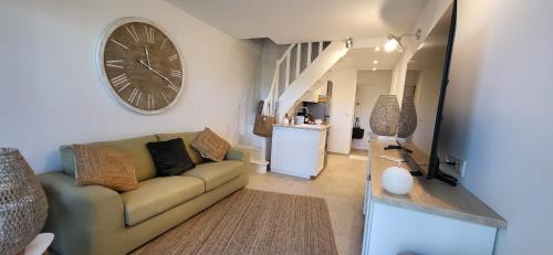 un salon avec un canapé et une horloge au mur dans l'établissement La Romantique Villa, au Grau-du-Roi