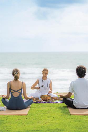 a group of three people sitting on the beach doing yoga at Meliá Phuket Mai Khao in Mai Khao Beach