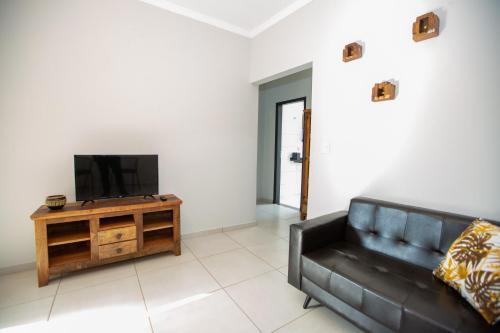 a living room with a black couch and a tv at Jahu Center Village in Jaú